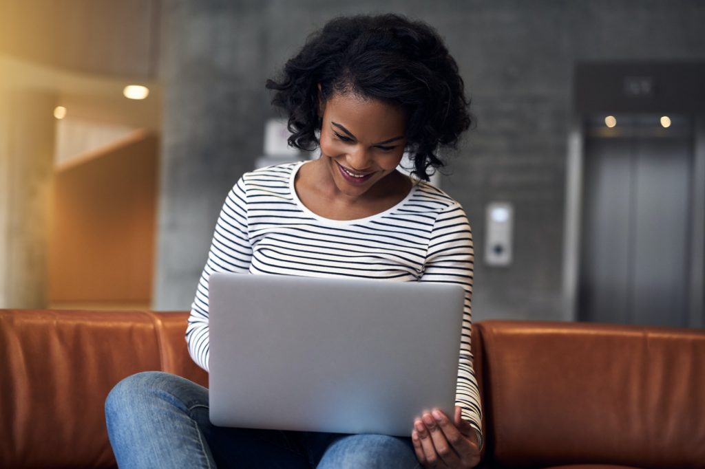 Smiling young African college student using a laptop at school