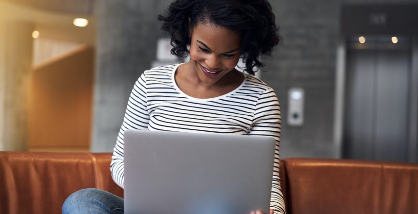 Smiling young African college student using a laptop at school